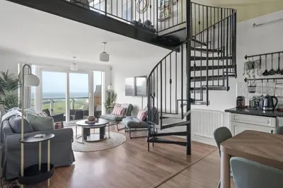 a living room with a spiral staircase in a apartment at Apartment Sea Views & Parking Walk to Fistral in Newquay