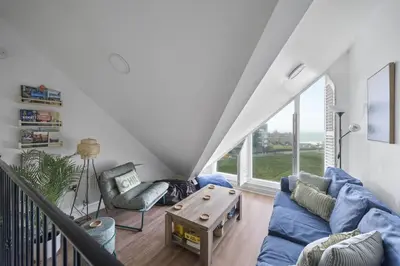 a living room with a blue couch and a table at Apartment Sea Views & Parking Walk to Fistral in Newquay