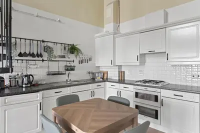 a kitchen with white cabinets and a wooden table at Apartment Sea Views & Parking Walk to Fistral in Newquay