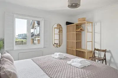 a white bedroom with a bed with towels on it at Apartment Sea Views & Parking Walk to Fistral in Newquay