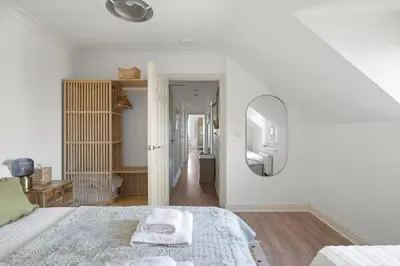 a white bedroom with a bed and a mirror at Apartment Sea Views & Parking Walk to Fistral in Newquay