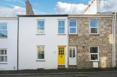 a white house with a yellow door at Dan's Den in St Ives