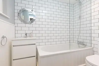 a white bathroom with a tub and a mirror at Dan's Den in St Ives