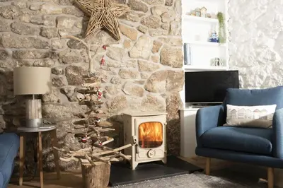 a fireplace in a living room with a stone wall at Happy Days Cottage - Free WiFi - Minutes from Harbour & Beaches - Pets Welcome in St Ives