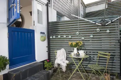 a patio with a blue door and a table with chairs at Happy Days Cottage - Free WiFi - Minutes from Harbour & Beaches - Pets Welcome in St Ives