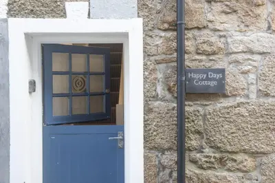 a blue door with a sign in front of a stone building at Happy Days Cottage - Free WiFi - Minutes from Harbour & Beaches - Pets Welcome in St Ives