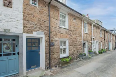 a brick building with a blue door on a street at Happy Days Cottage - Free WiFi - Minutes from Harbour & Beaches - Pets Welcome in St Ives
