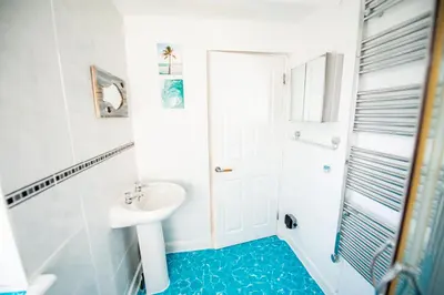 a white bathroom with a sink and a shower at Seaside Home with Parking Near Tolcarne Beach in Newquay