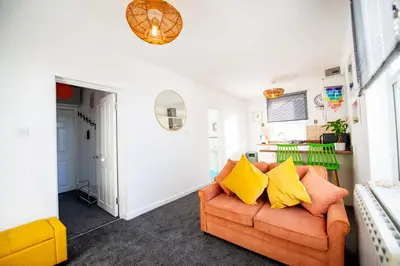 a living room with an orange couch with yellow pillows at Seaside Home with Parking Near Tolcarne Beach in Newquay