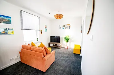 a living room with a couch and a tv at Seaside Home with Parking Near Tolcarne Beach in Newquay