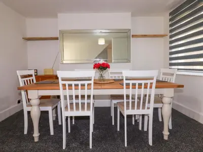 a dining room table with white chairs and a mirror at Trevarthian in St Austell