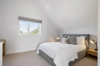 a white bedroom with a bed and a window at Modern Home with Stunning Gannel Estuary Views in Newquay
