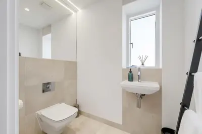 a white bathroom with a toilet and a sink at Modern Home with Stunning Gannel Estuary Views in Newquay