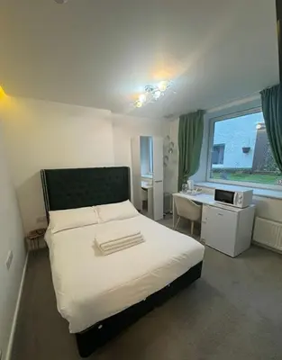 a bedroom with a bed and a desk and a window at Dancenter Tolcarne Beach hotel in Newquay