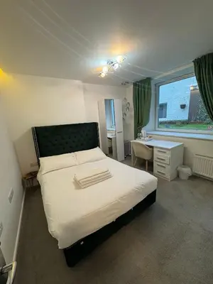 a bedroom with a bed and a desk and a window at Dancenter Tolcarne Beach hotel in Newquay