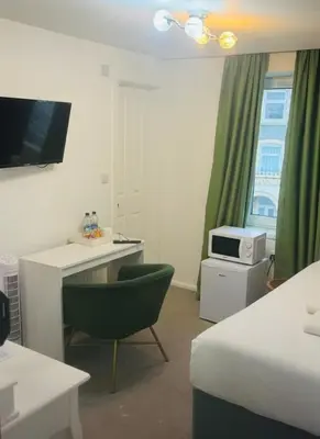 a room with a bed and a desk and a microwave at Dancenter Tolcarne Beach hotel in Newquay