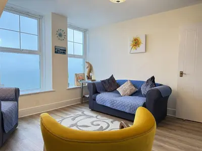 a living room with a blue couch and a yellow chair at Draycott Dreams in St Ives