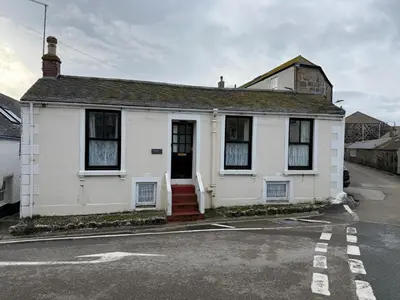 a white house with a red door on a street at Grannys in St Ives in St Ives