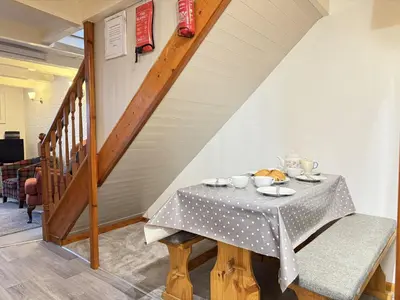 a dining room with a table and a staircase at Grannys in St Ives in St Ives