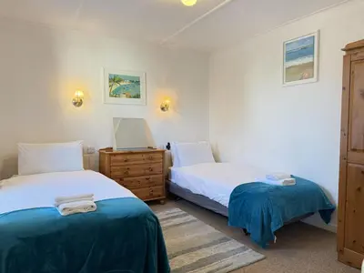 a bedroom with two beds and a dresser and towels at Grannys in St Ives in St Ives