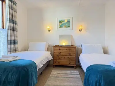 a bedroom with two beds and a dresser with a laptop on it at Grannys in St Ives in St Ives