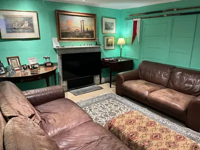a living room with a leather couch and a fireplace at Trehaverne Cottage Truro in Truro