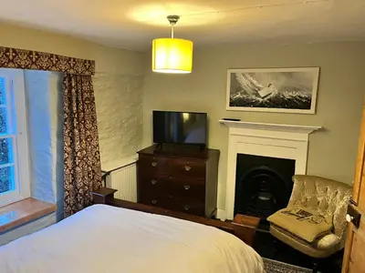 a bedroom with a bed and a tv and a fireplace at Trehaverne Cottage Truro in Truro