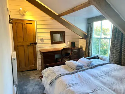 a bedroom with a bed and a desk and a window at Trehaverne Cottage Truro in Truro