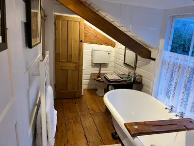 a bathroom with a bath tub in a tiny house at Trehaverne Cottage Truro in Truro