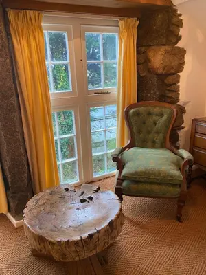 a living room with a chair and a wooden stump coffee table at Relaxing historic Roncon's Villa, The Paddock in Perranuthnoe