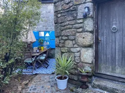 a patio with a table and a bench next to a stone wall at The Hexagon House in Penzance
