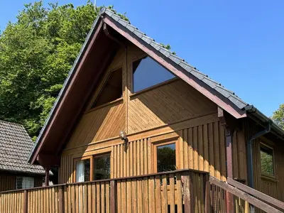 a wooden house with a fence and trees at Cornish Woodland Retreat in Bodmin
