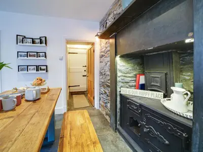 a kitchen with a wooden table and a large fireplace at Church Hill House in Port Isaac