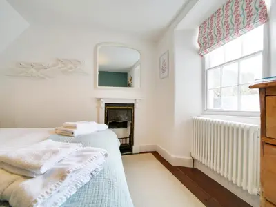 a bedroom with two beds and a fireplace at Church Hill House in Port Isaac