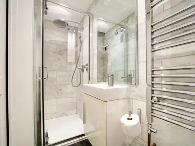 a white bathroom with a sink and a shower at Church Hill House in Port Isaac