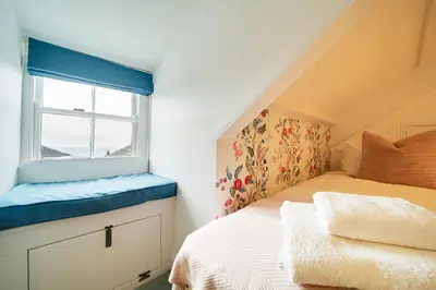 a bedroom with a bed and a window at Church Hill House in Port Isaac
