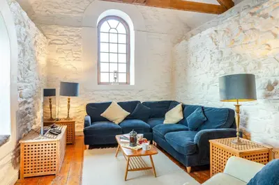 a living room with a blue couch and a stone wall at 3 Bed in Porthtowan oc-e34620 in Porthtowan