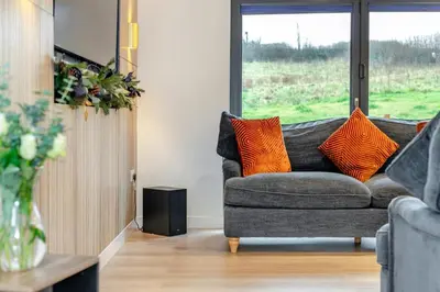 a living room with a gray couch with orange pillows at 4 Bed in St. Gennys oc-p34626 in Crackington Haven