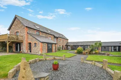 an exterior view of a large brick building with a yard at 1 Bed in St. Gennys oc-c34627 in Crackington Haven