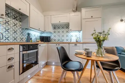 a kitchen with white cabinets and a table and chairs at 1 Bed in St. Gennys oc-c34627 in Crackington Haven