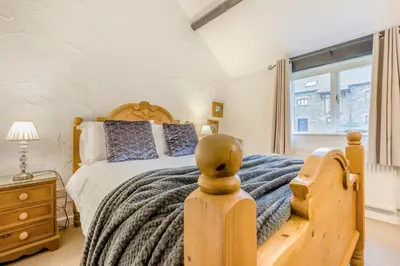 a bedroom with a wooden bed and a window at 2 Bed in St. Gennys oc-o34630 in Crackington Haven