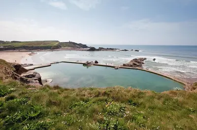 a swimming pool on a beach next to the ocean at 2 Bed in St. Gennys oc-o34630 in Crackington Haven