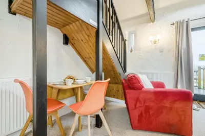 a living room with a red chair and a table at 2 Bed in St. Gennys oc-p34632 in Crackington Haven