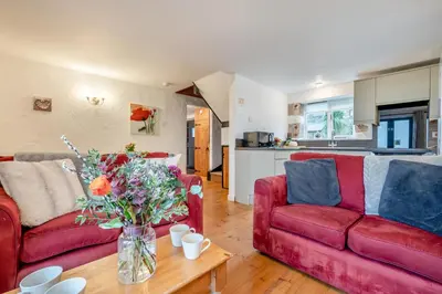 a living room with two red couches and a table with flowers at 3 Bed in St. Gennys oc-a34633 in Crackington Haven