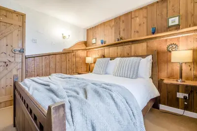 a bedroom with a large bed with a wooden wall at 3 Bed in St. Gennys oc-a34633 in Crackington Haven