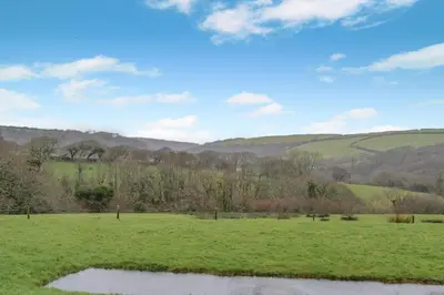 a field with a pond in the middle of it at 3 Bed in St. Gennys oc-a34633 in Crackington Haven