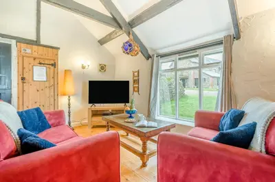 a living room with two red chairs and a tv at 1 Bed in St. Gennys oc-v34634 in Crackington Haven