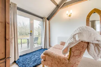 a living room with a chair and a sliding glass door at 1 Bed in St. Gennys oc-v34634 in Crackington Haven
