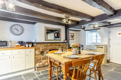 a kitchen with a wooden table and a fireplace at 1 Bed in Looe oc-l30002 in Looe