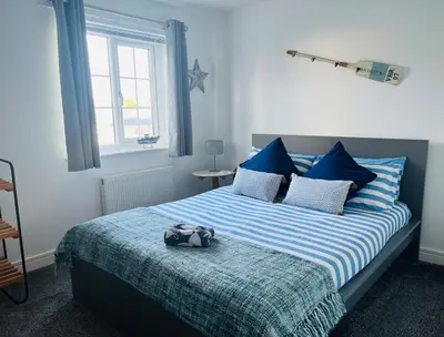 a bedroom with a bed with blue and white pillows at Little Sea View Duporth - 3 bed, gated beach, Nr Eden Project in Charlestown